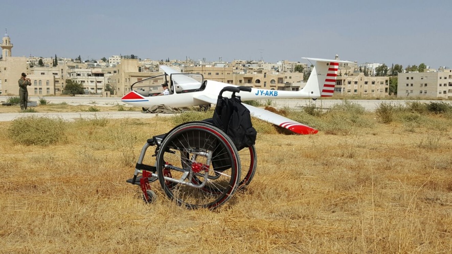 imagen de una silla de ruedas vacía y al fondo el avión con su piloto