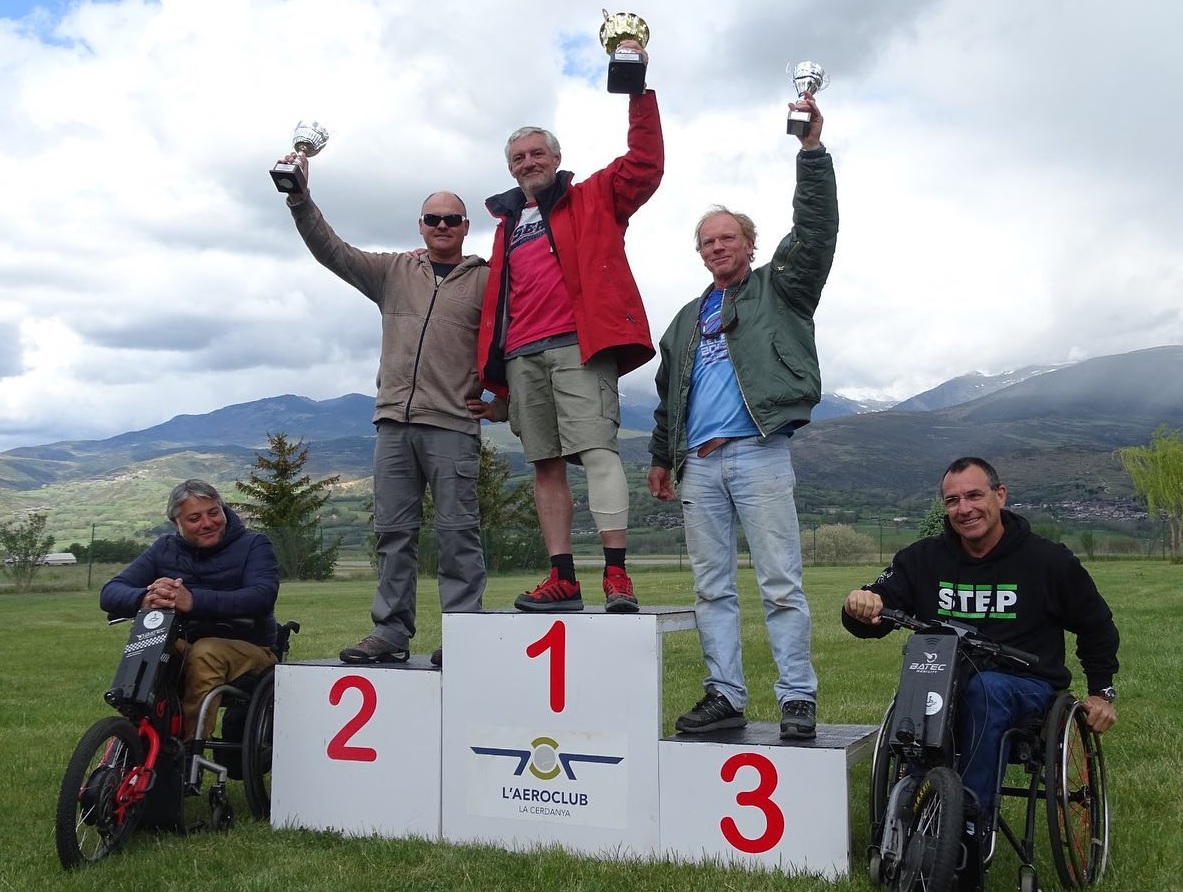 Fotografía de los ganadores en el podium con las copas en alzadas